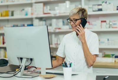person working in pharmacy on phone and looking at computer