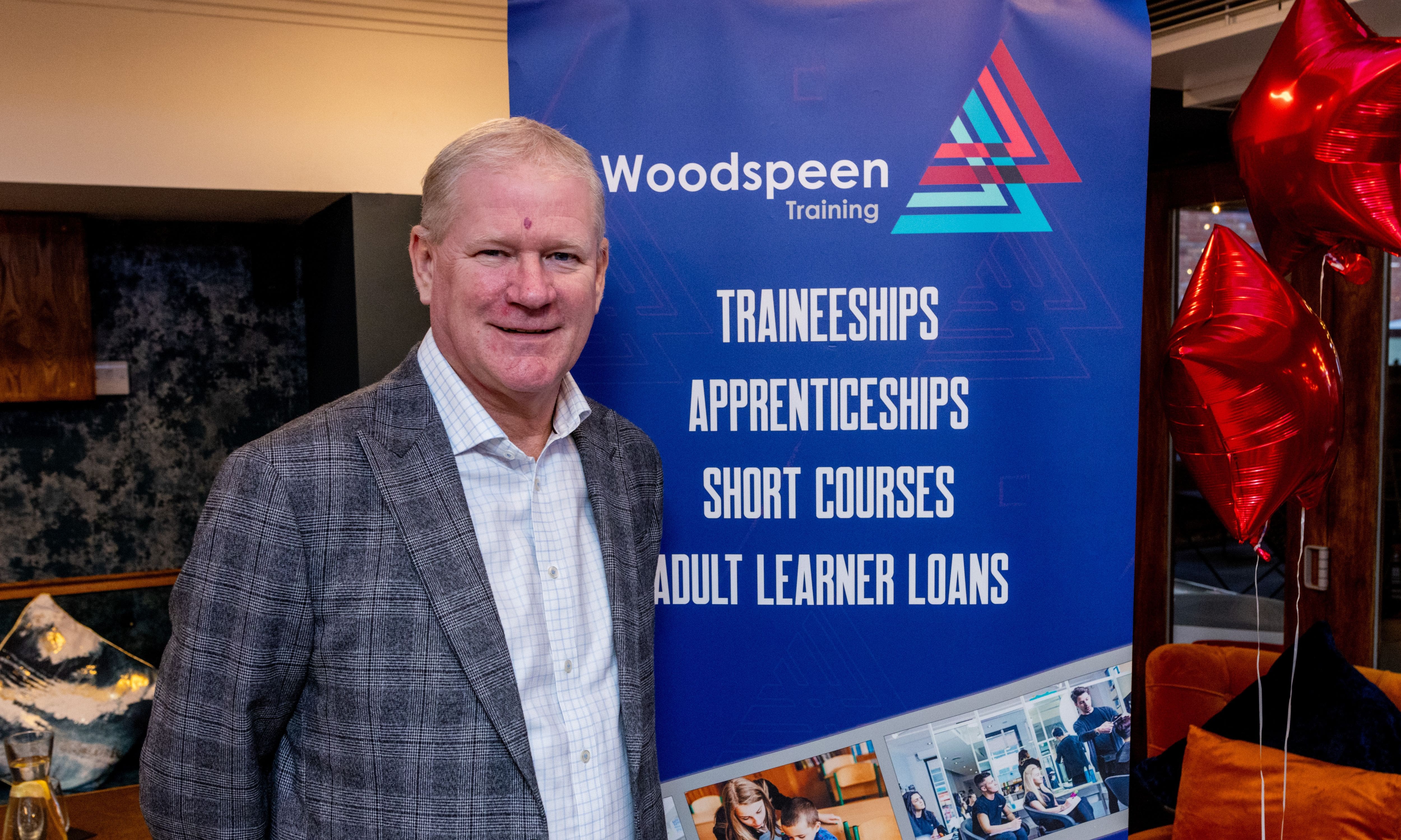 John Deaville standing in front of a Woodspeen Training banner 