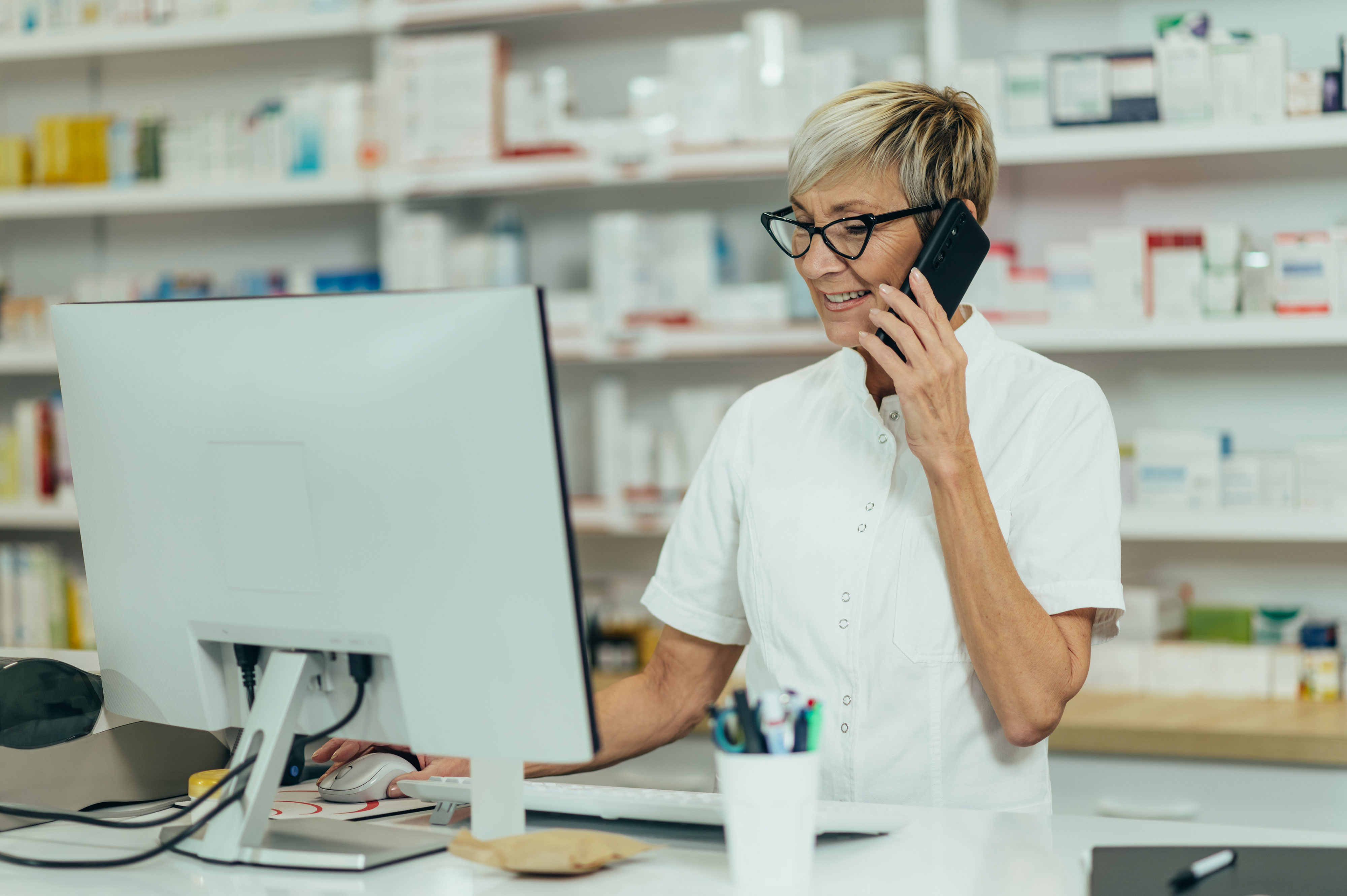 person working in pharmacy on phone and looking at computer