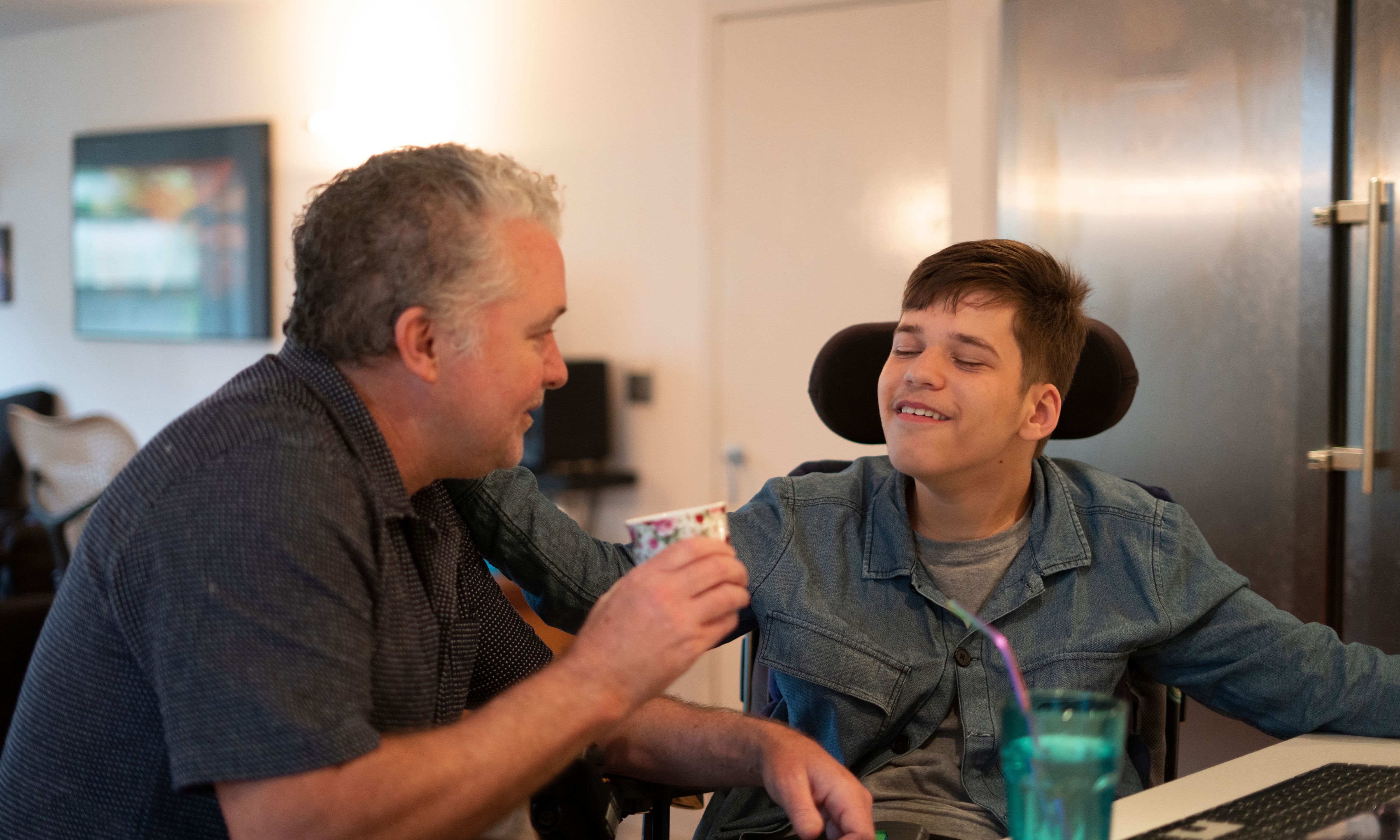 Two people, one older in wheel chair that requires care