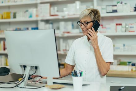 person working in pharmacy on phone and looking at computer